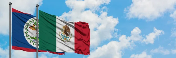 Belize e la bandiera del Messico sventolano nel vento contro il bianco cielo blu nuvoloso insieme. Concetto di diplomazia, relazioni internazionali . — Foto Stock