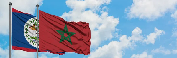 Bandera de Belice y Marruecos ondeando en el viento contra el cielo azul nublado blanco juntos. Concepto diplomático, relaciones internacionales . — Foto de Stock