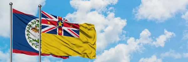 Bandera de Belice y Niue ondeando en el viento contra el cielo azul nublado blanco juntos. Concepto diplomático, relaciones internacionales . — Foto de Stock