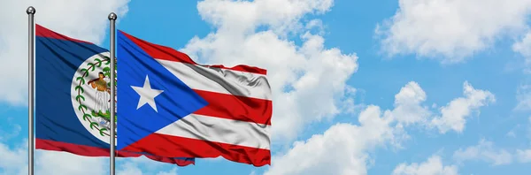 Belize und puerto rico fahne wehen gemeinsam im wind vor weißem wolkenblauem himmel. Diplomatie-Konzept, internationale Beziehungen. — Stockfoto