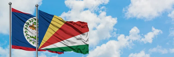 Bandera de Belice y Seychelles ondeando en el viento contra el cielo azul nublado blanco juntos. Concepto diplomático, relaciones internacionales . — Foto de Stock