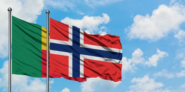 Bandera de Benin y Bouvet Islands ondeando en el viento contra el cielo azul nublado blanco juntos. Concepto diplomático, relaciones internacionales . — Foto de Stock