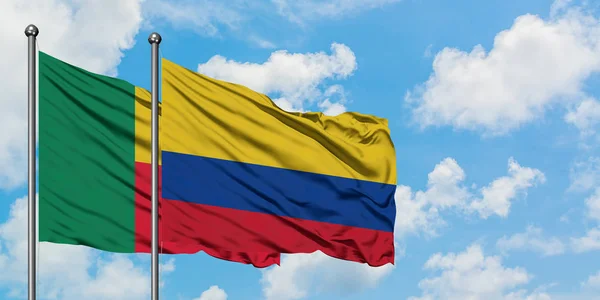 Bandera de Benín y Colombia ondeando en el viento contra el cielo azul nublado blanco juntos. Concepto diplomático, relaciones internacionales . — Foto de Stock