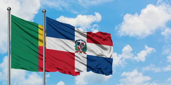 Bandera de Benín y República Dominicana ondeando en el viento contra el cielo azul nublado blanco juntos. Concepto diplomático, relaciones internacionales . — Foto de Stock