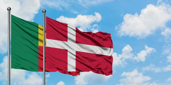 Benin a Dánská vlajka mávali ve větru proti bíle zatažené modré obloze. Diplomacie, mezinárodní vztahy. — Stock fotografie