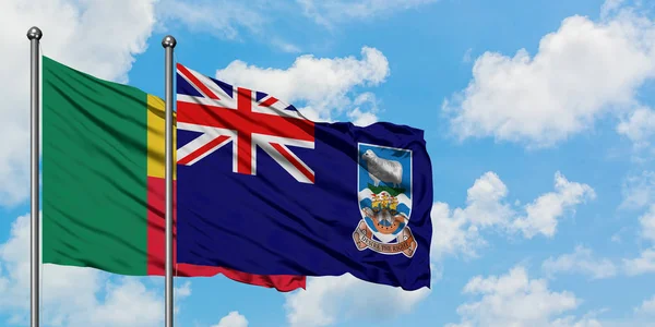 Bandera de Benín y las Islas Malvinas ondeando en el viento contra el cielo azul nublado blanco juntos. Concepto diplomático, relaciones internacionales . — Foto de Stock