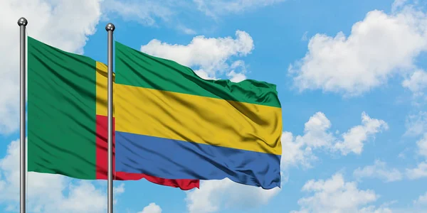 Bandera de Benín y Gabón ondeando en el viento contra el cielo azul nublado blanco juntos. Concepto diplomático, relaciones internacionales . — Foto de Stock