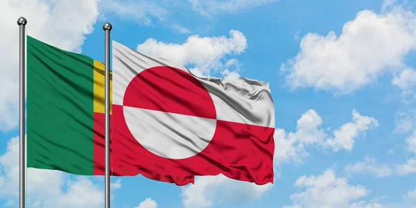 Bandera de Benín y Groenlandia ondeando en el viento contra el cielo azul nublado blanco juntos. Concepto diplomático, relaciones internacionales . — Foto de Stock
