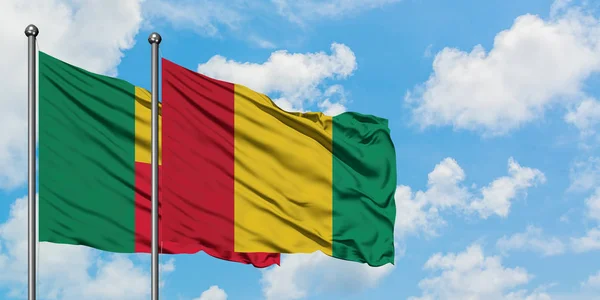 Bandera de Benín y Guinea ondeando en el viento contra el cielo azul nublado blanco juntos. Concepto diplomático, relaciones internacionales . — Foto de Stock
