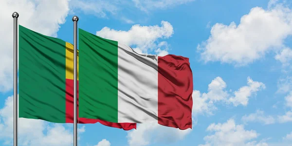 Bandera de Benín e Italia ondeando en el viento contra el cielo azul nublado blanco juntos. Concepto diplomático, relaciones internacionales . — Foto de Stock