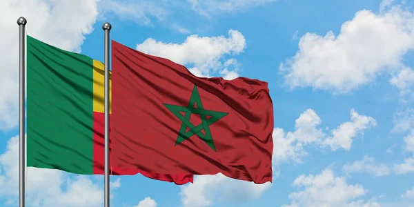 Bandera de Benín y Marruecos ondeando en el viento contra el cielo azul nublado blanco juntos. Concepto diplomático, relaciones internacionales . — Foto de Stock