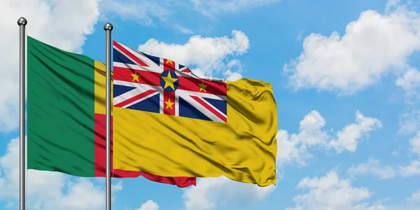 Bandera de Benín y Niue ondeando en el viento contra el cielo azul nublado blanco juntos. Concepto diplomático, relaciones internacionales . — Foto de Stock