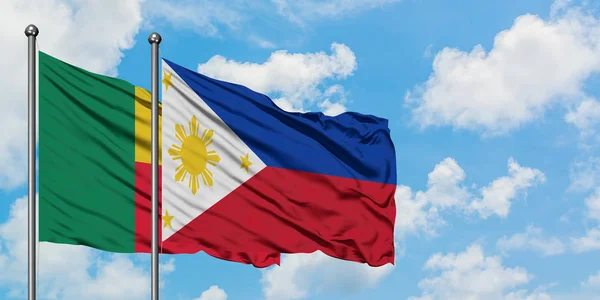 Bandera de Benín y Filipinas ondeando en el viento contra el cielo azul nublado blanco juntos. Concepto diplomático, relaciones internacionales . — Foto de Stock