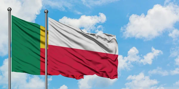 Bandera de Benín y Polonia ondeando en el viento contra el cielo azul nublado blanco juntos. Concepto diplomático, relaciones internacionales . — Foto de Stock