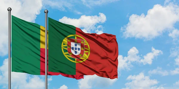 Bandera de Benín y Portugal ondeando en el viento contra el cielo azul nublado blanco juntos. Concepto diplomático, relaciones internacionales . — Foto de Stock