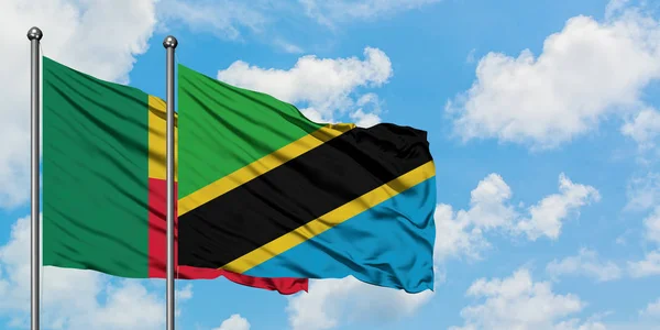 Bandera de Benín y Tanzania ondeando en el viento contra el cielo azul nublado blanco juntos. Concepto diplomático, relaciones internacionales . — Foto de Stock