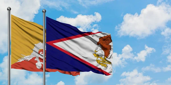Bandera de Bután y Samoa Americana ondeando en el viento contra el cielo azul nublado blanco juntos. Concepto diplomático, relaciones internacionales . —  Fotos de Stock