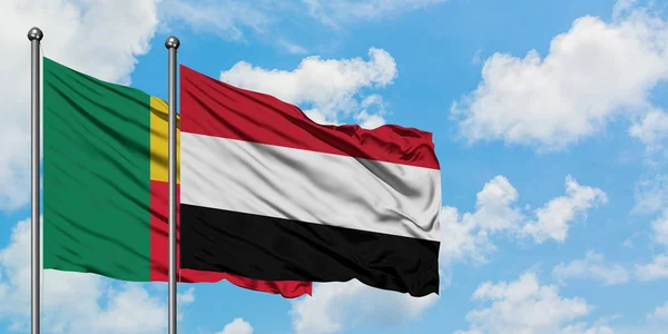 Bandera de Benín y Yemen ondeando en el viento contra el cielo azul nublado blanco juntos. Concepto diplomático, relaciones internacionales . — Foto de Stock
