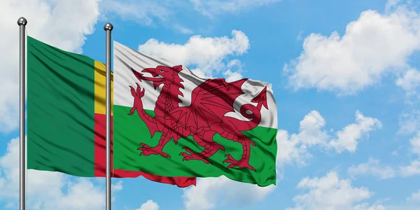 Bandeira do Benim e do País de Gales agitando no vento contra o céu azul nublado branco juntos. Conceito de diplomacia, relações internacionais . — Fotografia de Stock