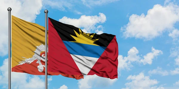 Bandera de Bután y Antigua y Barbuda ondeando en el viento contra el cielo azul nublado blanco juntos. Concepto diplomático, relaciones internacionales . — Foto de Stock