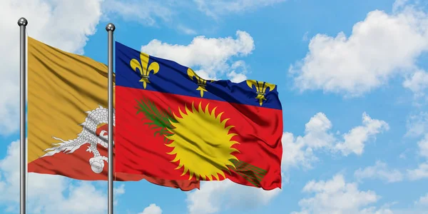 Bandera de Bután y Guadalupe ondeando en el viento contra el cielo azul nublado blanco juntos. Concepto diplomático, relaciones internacionales . — Foto de Stock