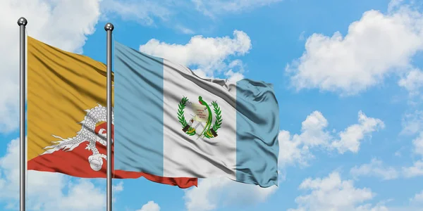 Bhutan och Guatemala sjunker vinka i vinden mot vit grumlig blå himmel tillsammans. Diplomatisk koncept, internationella relationer. — Stockfoto