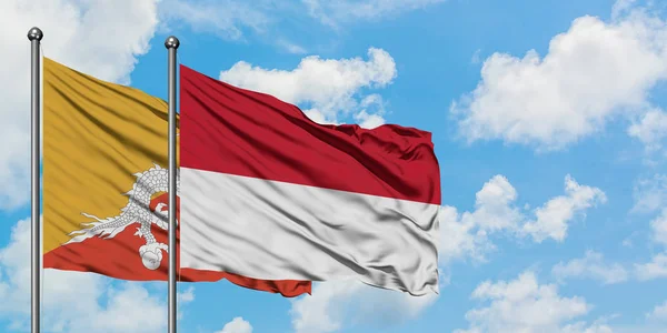 Bhutan and Indonesia flag waving in the wind against white cloudy blue sky together. Diplomacy concept, international relations. — Stock Photo, Image