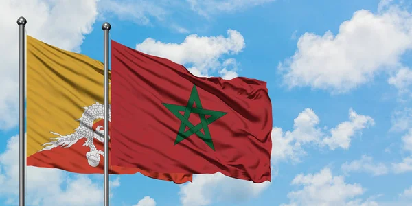 Bandera de Bután y Marruecos ondeando en el viento contra el cielo azul nublado blanco juntos. Concepto diplomático, relaciones internacionales . — Foto de Stock