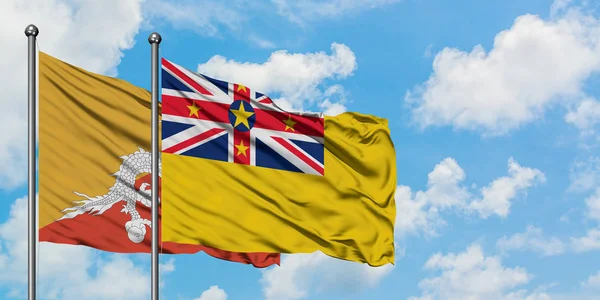 Bandera de Bután y Niue ondeando en el viento contra el cielo azul nublado blanco juntos. Concepto diplomático, relaciones internacionales . — Foto de Stock