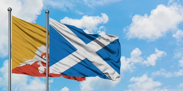 Bhutan and Scotland flag waving in the wind against white cloudy blue sky together. Diplomacy concept, international relations.