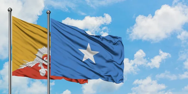 Bandera de Bután y Somalia ondeando en el viento contra el cielo azul nublado blanco juntos. Concepto diplomático, relaciones internacionales . — Foto de Stock