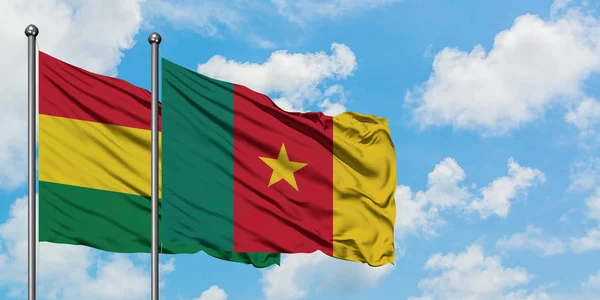 Bandera de Bolivia y Camerún ondeando en el viento contra el cielo azul nublado blanco juntos. Concepto diplomático, relaciones internacionales . — Foto de Stock