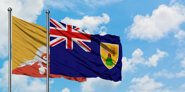 Bandera de Bután y las Islas Turcas y Caicos ondeando en el viento contra el cielo azul nublado blanco juntos. Concepto diplomático, relaciones internacionales . — Foto de Stock