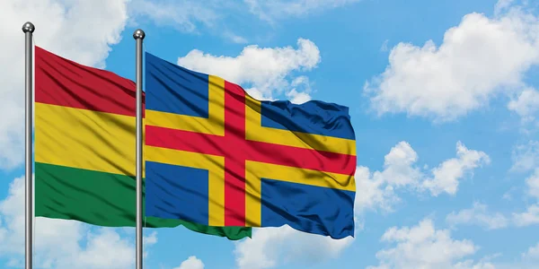 Bandera de Bolivia e Islas Aland ondeando en el viento contra el cielo azul nublado blanco juntos. Concepto diplomático, relaciones internacionales . — Foto de Stock