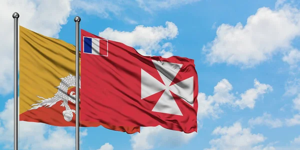 Bandera de Bután y Wallis y Futuna ondeando en el viento contra el cielo azul nublado blanco juntos. Concepto diplomático, relaciones internacionales . — Foto de Stock