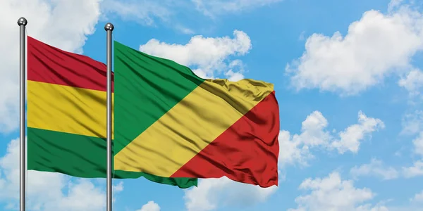 Bandera de Bolivia y República del Congo ondeando en el viento contra el cielo azul nublado blanco juntos. Concepto diplomático, relaciones internacionales . — Foto de Stock
