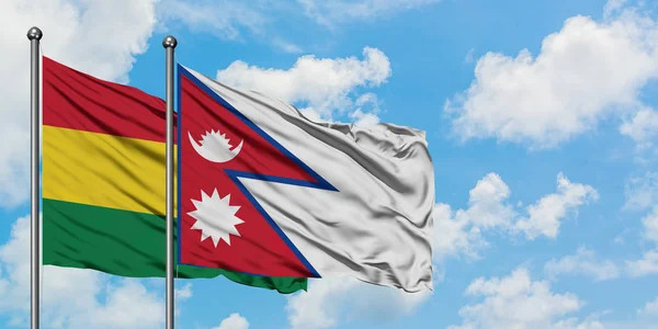 Bandera de Bolivia y Nepal ondeando en el viento contra el cielo azul nublado blanco juntos. Concepto diplomático, relaciones internacionales . — Foto de Stock
