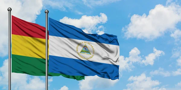 Bolivien und Nicaragua schwenken gemeinsam die Flagge im Wind vor dem wolkenverhangenen blauen Himmel. Diplomatie-Konzept, internationale Beziehungen. — Stockfoto