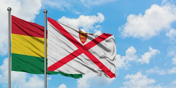 Bandera de Bolivia y Jersey ondeando en el viento contra el cielo azul nublado blanco juntos. Concepto diplomático, relaciones internacionales . — Foto de Stock