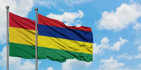 Bandera de Bolivia y Mauricio ondeando en el viento contra el cielo azul nublado blanco juntos. Concepto diplomático, relaciones internacionales . — Foto de Stock