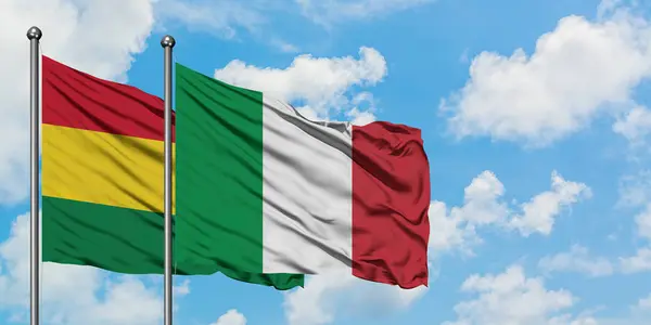 Bandera de Bolivia e Italia ondeando en el viento contra el cielo azul nublado blanco juntos. Concepto diplomático, relaciones internacionales . — Foto de Stock