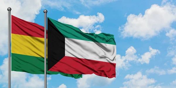 Bandera de Bolivia y Kuwait ondeando en el viento contra el cielo azul nublado blanco juntos. Concepto diplomático, relaciones internacionales . — Foto de Stock