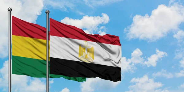 Bandera de Bolivia y Egipto ondeando en el viento contra el cielo azul nublado blanco juntos. Concepto diplomático, relaciones internacionales . — Foto de Stock