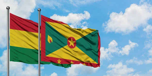 Bandera de Bolivia y Granada ondeando en el viento contra el cielo azul nublado blanco juntos. Concepto diplomático, relaciones internacionales . — Foto de Stock