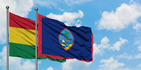 Bolivya ve Guam bayrağı birlikte beyaz bulutlu mavi gökyüzüne karşı rüzgarda sallayarak. Diplomasi kavramı, uluslararası ilişkiler. — Stok fotoğraf