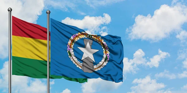 Bandera de Bolivia y las Islas Marianas del Norte ondeando en el viento contra el cielo azul nublado blanco juntos. Concepto diplomático, relaciones internacionales . — Foto de Stock