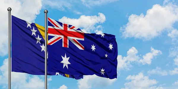 Bosnien-Herzegowina und Australien schwenken gemeinsam die Flagge im Wind vor dem wolkenverhangenen blauen Himmel. Diplomatie-Konzept, internationale Beziehungen. — Stockfoto