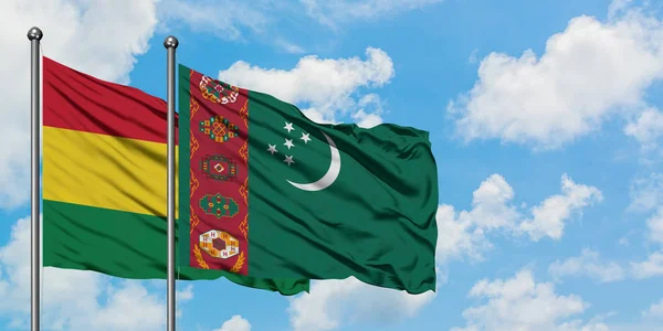 Bandera de Bolivia y Turkmenistán ondeando en el viento contra el cielo azul nublado blanco juntos. Concepto diplomático, relaciones internacionales . — Foto de Stock