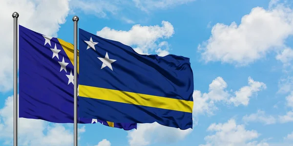Drapelul Bosniei Herțegovina și Curacao flutură în vânt împotriva cerului albastru și noros alb împreună. Conceptul de diplomație, relațiile internaționale . — Fotografie, imagine de stoc