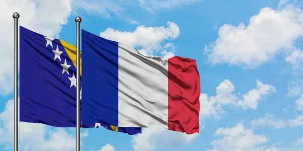 Bandera de Bosnia Herzegovina y Francia ondeando en el viento contra el cielo azul nublado blanco juntos. Concepto diplomático, relaciones internacionales . — Foto de Stock